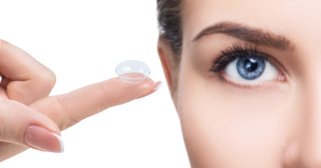 Contact lens on index finger near beautiful female face.の写真素材