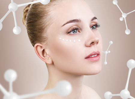 Young woman with cream dots among white molecules.の写真素材