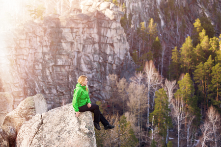 Young woman sitting on cliffs edge.の写真素材