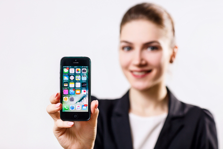 Young woman holds black Apple iPhone 5 display in hand.のeditorial素材