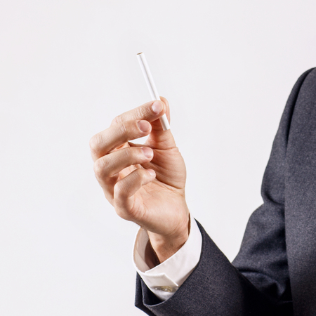 Businessman holds cigarette in hand.の写真素材