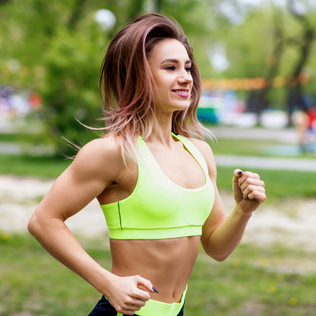 Beautiful young woman running in the green park.の写真素材
