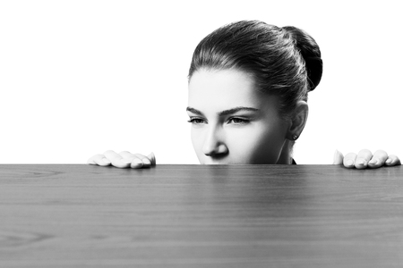 Woman peeping under the edge of wooden table.の写真素材