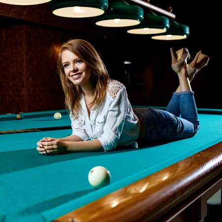 Young woman lying on the green billiard table.の写真素材