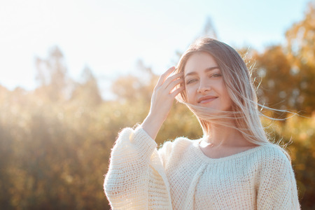 Pretty girl posing on camera and enjoying sunny autumn day.の写真素材