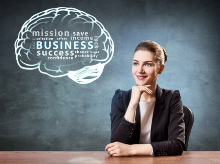 Business woman sits at the table near infographic brain.の写真素材