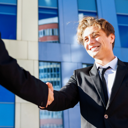 Professional businessman and woman in formal suit shaking hands outdoors.の写真素材
