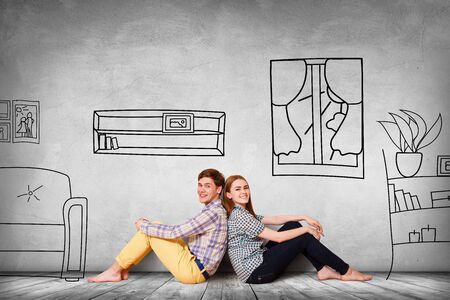 Happy couple sitting on the floor among painted furniture on the wall.の写真素材
