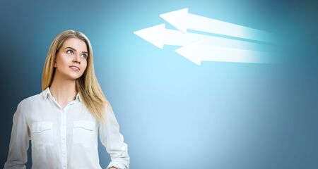 Business woman looks on big arrows over blue digital background.の写真素材