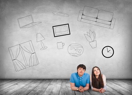 Young couple lying on the floor among painted furniture on the wall.の写真素材