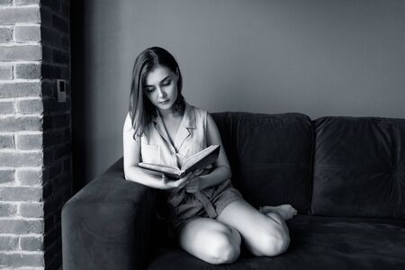 Young woman sits and relax on the couch and looks in her diary.の写真素材