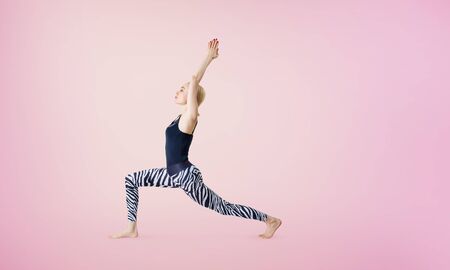 Adult woman doing yoga exercise in warrior position.の写真素材