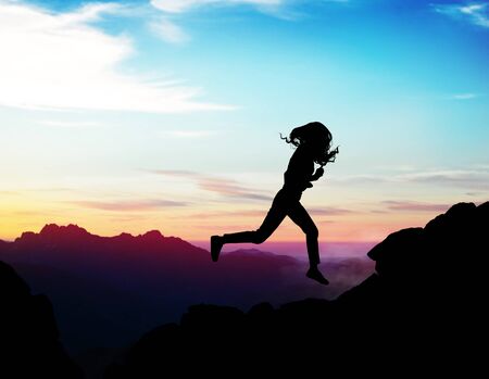 Black silhouette of woman running forward on the rock. Business risk concept.の写真素材