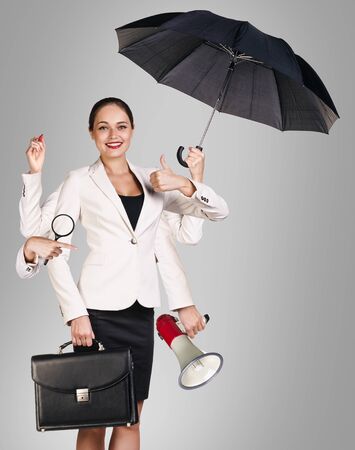 Young business woman multitasking with different staff in hands.の写真素材