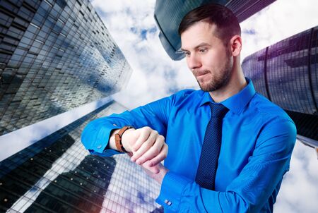 Businessman check smartwatch over cityscape background.の写真素材