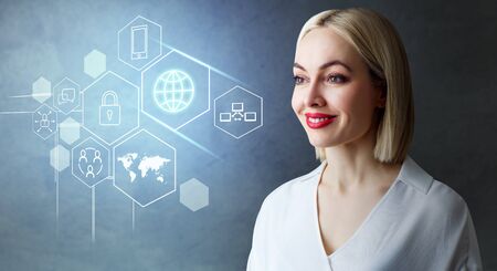Blonde business woman looks on the different digital icons.の写真素材