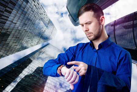 Businessman check smartwatch over cityscape background.の写真素材