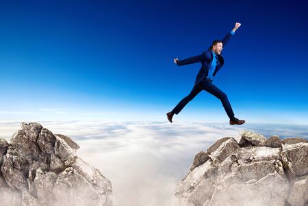 Young businessman flying through the gap among mountains.の写真素材