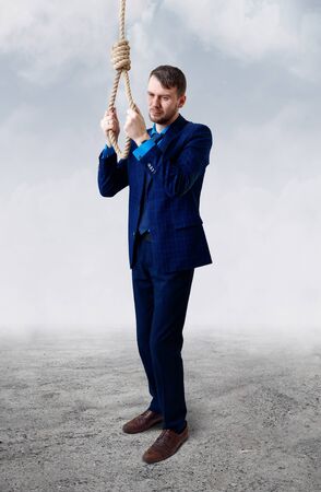 Depressed businessman wearing rope loop committing suicide.の写真素材