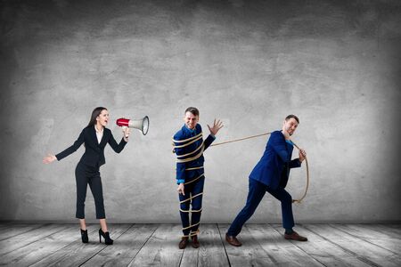 Businesswoman gives orders and manager pulls tied himself.の写真素材