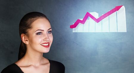 Business woman looks on increase schedule with growth arrow.の写真素材