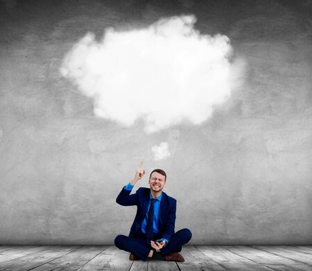 Angry businessman sitting on the floor and pointing on white cloud.の写真素材