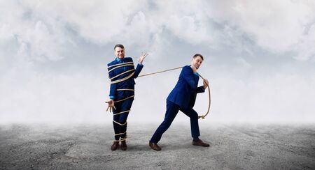 Angry businessman pulls tied himself with a rope.の写真素材