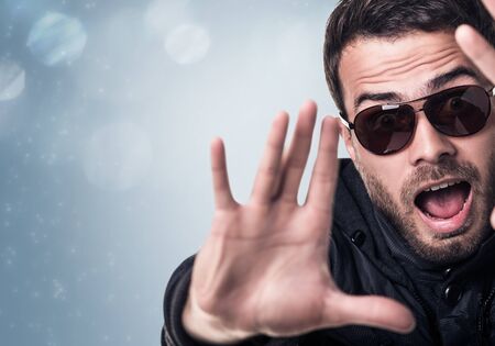 Surprised man in sunglasses shows stop sign by hands.の写真素材