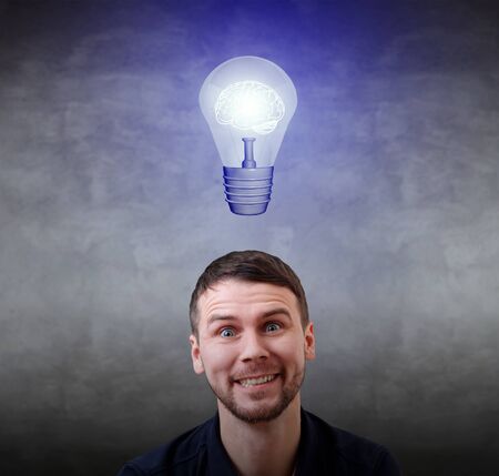 Young businessman smiling with light bulb over head.の写真素材