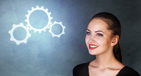 Business woman looks on working cogwheels.の写真素材