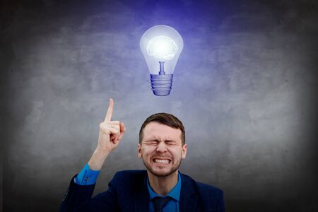 Young businessman point finger on light bulb over head.の写真素材