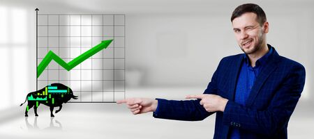 Smiling businessman pointing on silhouette bull financial icon.の写真素材