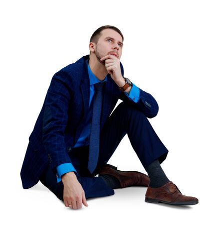 Young thoughtful businessman sitting on the floor.の写真素材
