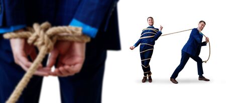Angry businessman pulls tied himself with a rope.の写真素材