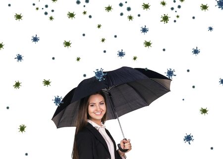Young smiling businesswoman under umbrella among coronavirus cells.の写真素材