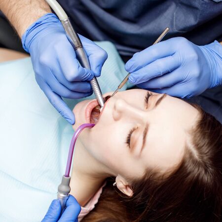 Dentist treating teeth to young woman patient in clinic.の写真素材