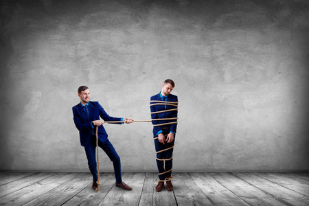 Angry businessman pulls tied himself with a rope.