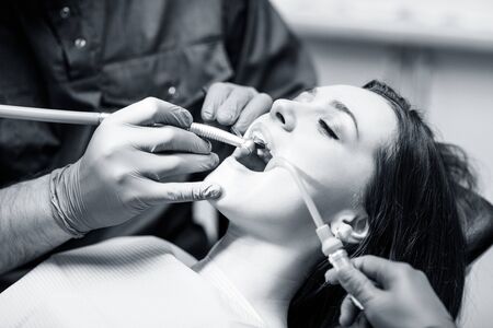 Dentist treating teeth to young woman patient in clinic.の写真素材