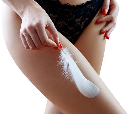 Woman holds the feather over hips background. Women health and intimate hygiene. Epilation Concept.の写真素材