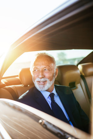 Senior business man sitting in his limousine. Business concept. Back light.