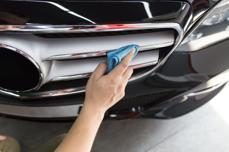 A man cleaning car with microfiber cloth, car detailing (or valeting) concept.