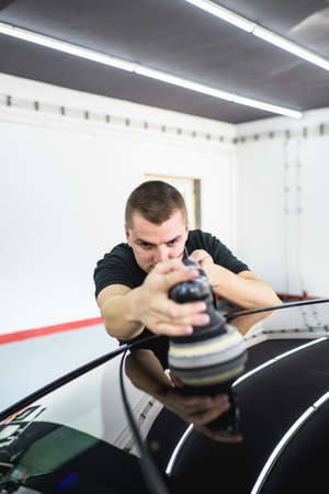 Car detailing - Worker with orbital polisher in auto repair shop.の写真素材