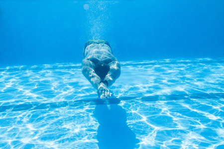Underwater enjoyment. Young man swimming underwater and diving in the swimming pool.