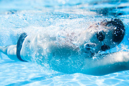 Underwater enjoyment. Young man swimming underwater and diving in the swimming pool.の写真素材