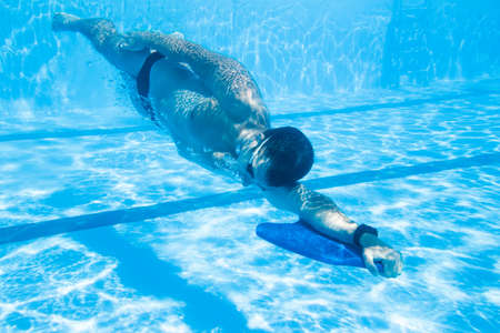 Underwater enjoyment. Young man swimming underwater and diving in the swimming pool.の写真素材