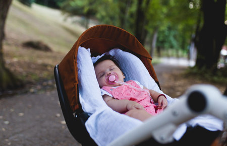 Beautiful baby girl sleeping outdoors in stroller.