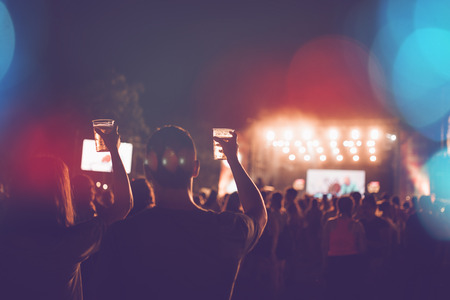 Silhouettes of festival concert crowd in front of bright stage lights.の写真素材