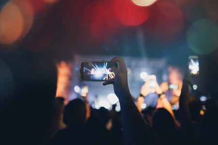 Silhouettes of festival concert crowd in front of bright stage lights.の写真素材