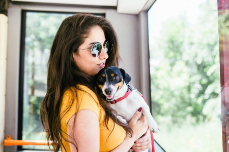 Beautiful young woman standing in city bus with her jack russell terrier.