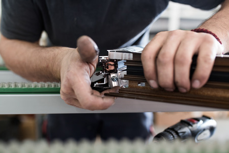 Factory for aluminum and PVC windows and doors production. Manual worker assembling PVC doors and windows.の写真素材